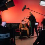 Netflix remporte l’enchère Warner Bros. à 82,7 milliards : Apple reste sur le banc A behind-the-scenes look at a filming crew setting up a scene indoors with lighting equipment.
