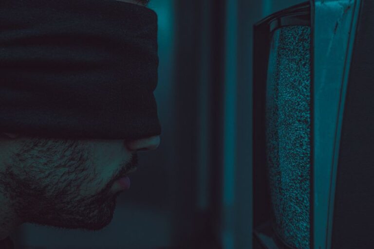 tvOS 26.2 disponible le 12 décembre 2025: mode enfants, Apple desserre la laisse A close-up of a blindfolded man facing a static television screen in a dark room.