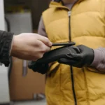 Tap to Pay sur iPhone arrive à Hong Kong le 9 décembre 2025: le terminal tient dans la main A close-up of a contactless payment made using a cellphone and a payment terminal held by a courier.