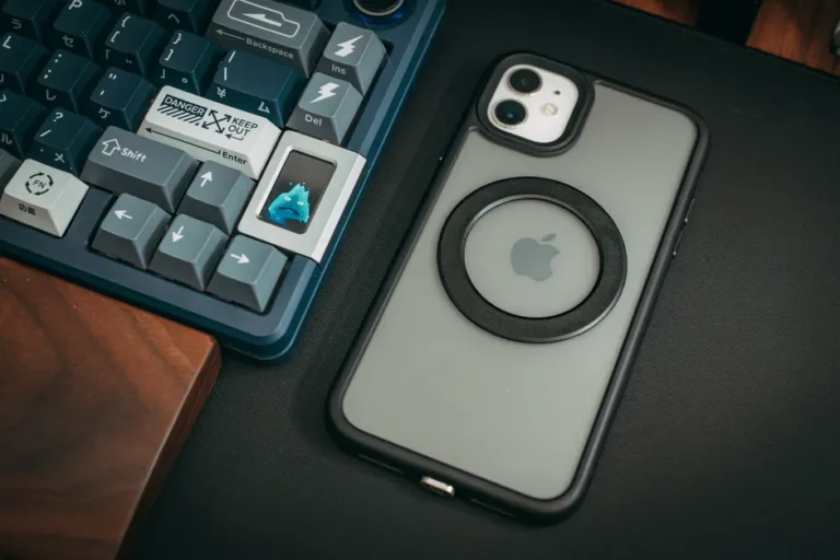 Clicks Power Keyboard : 2 150 mAh, 180 g et le clavier qui prend du poids A close-up of a custom keyboard with keycaps and a smartphone on a sleek desk setup.
