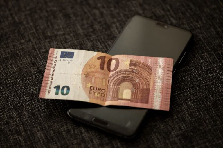 Apple Cash inspire des stickers irisés dans iMessage le 10 décembre, sans toucher aux paiements A close-up shot of a 10 euro banknote placed on a smartphone, highlighting currency and digital technology.