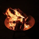 A close-up view of a campfire, showcasing vibrant flames against a dark night backdrop.