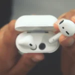 A close-up view of hands holding wireless earbuds in an open charging case.