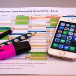 A desk setup featuring a planner, pens, and a smartphone displaying app icons, ideal for productivity.