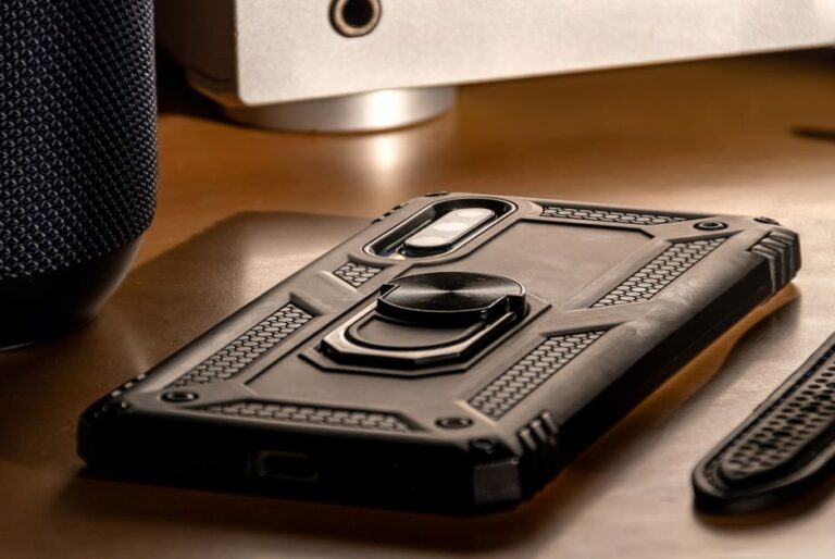 Black Friday 2025 : les coques Torras pour iPhone 17 passent en mode Ostand A detailed close-up view of a smartphone with a rugged case lying on a desk, showcasing modern technology.