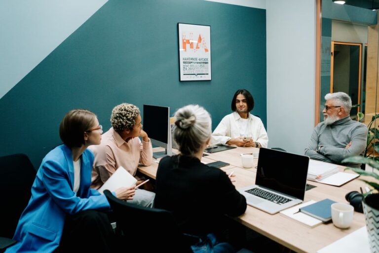 Apple rejoint la Tech Force US : deux ans pour ses managers, le jardin clos entrouvre A diverse group of professionals engaged in a dynamic meeting in a modern office environment.