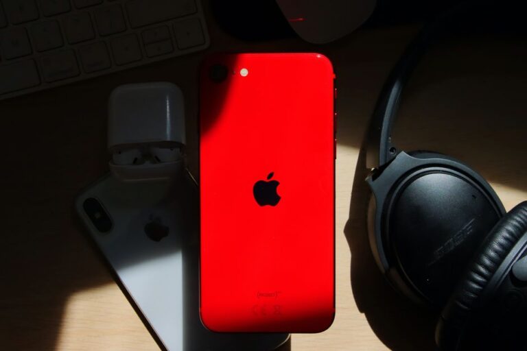 Fortnite reste hors de l’iPhone au Japon en 2025, les frais d’Apple coincent le retour A flat lay of a red iPhone surrounded by AirPods and Bose headphones on a wooden surface.