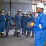 Apple met sa Manufacturing Academy en ligne le 8 décembre 2025, sans fabriquer d'iPhone A group of factory workers in safety gear receiving training indoors.