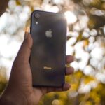 Sanchar Saathi sur iPhone : Apple refuse l'appli imposée en Inde A hand holding a smartphone outdoors with bokeh effect in the background.