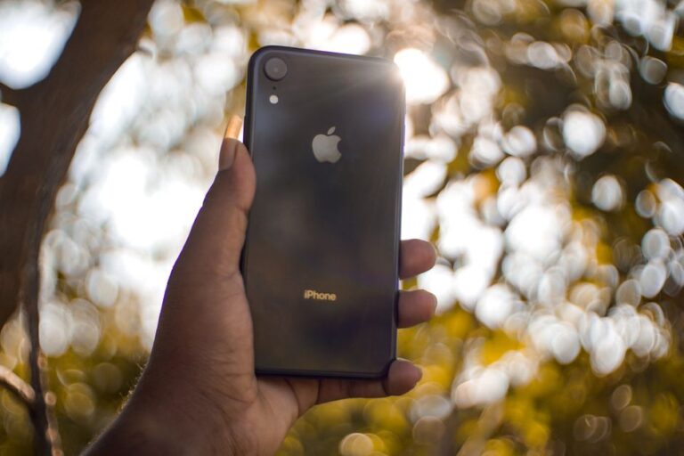 Sanchar Saathi sur iPhone : Apple refuse l’appli imposée en Inde A hand holding a smartphone outdoors with bokeh effect in the background.