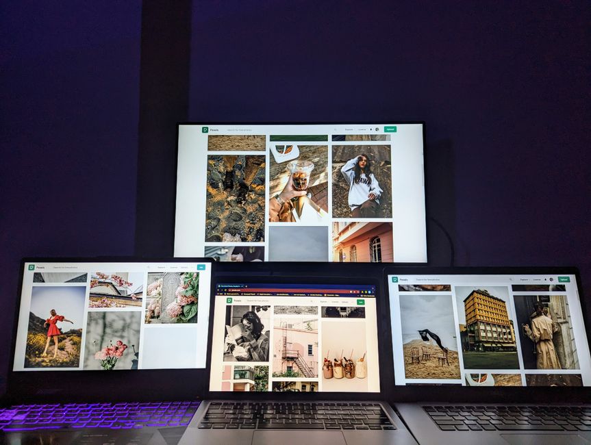 A high-tech workspace featuring three laptops and a monitor with various images displayed, highlighting technology and digital art.