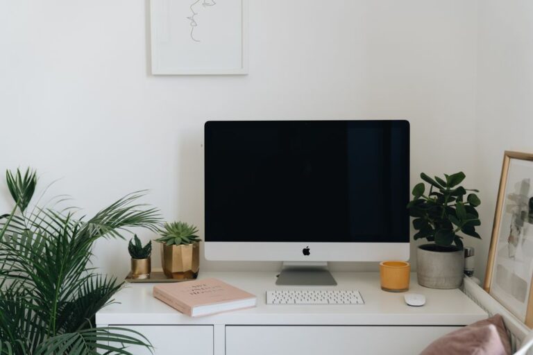 Bureau Apple minimaliste : l’iMac M1 tient bon en 2025 A minimalist home office desk featuring a computer, keyboard, and indoor plants.