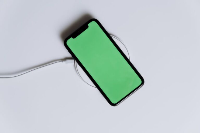 Chargeurs Kuxiu Qi2.2 à 25 W pour iPhone 17 : le câble fait la différence A minimalist smartphone with a green screen on a wireless charger, ideal for tech mockups.