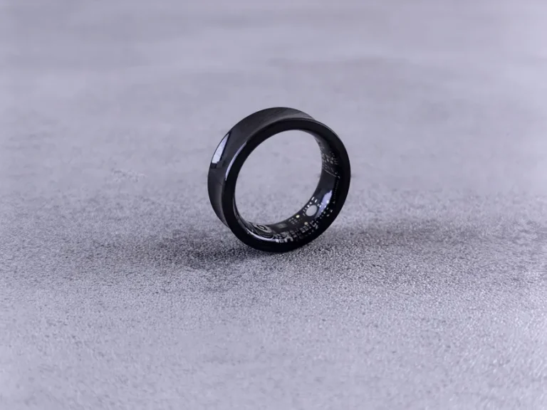 Pebble Index 01 : 75 dollars en précommande, zéro recharge A modern black smart ring with visible circuitry resting on a textured concrete surface.