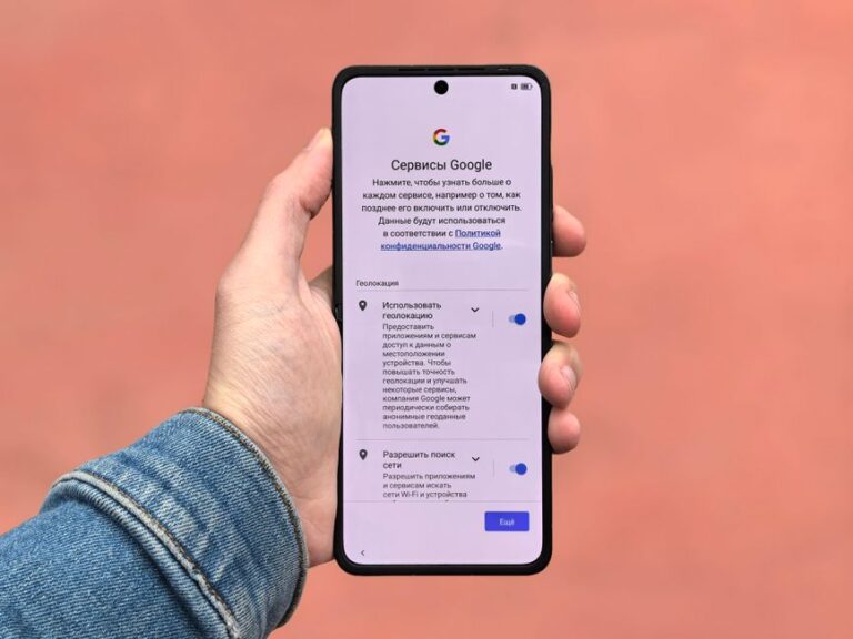 iOS 26.3 et macOS Tahoe 26.3 : Android entre par la fenêtre A person holding a smartphone displaying Google settings on a simple background.