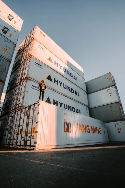 A person standing on Hyundai shipping containers at Brisbane port during day.