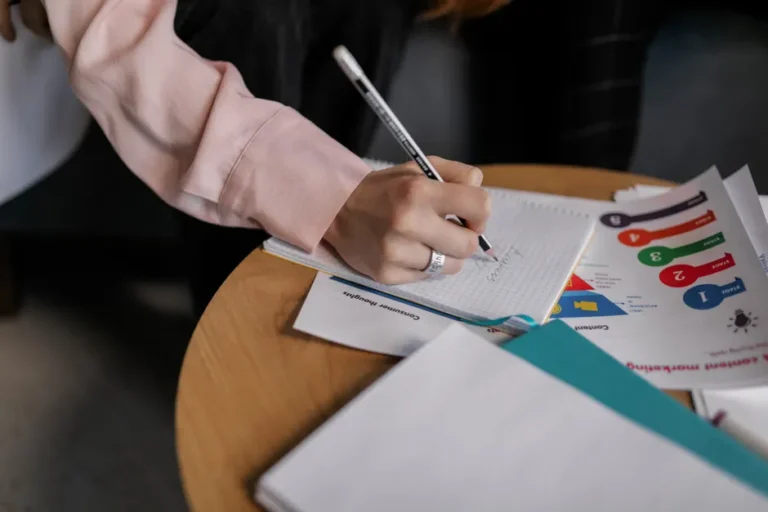 Apple Notes importe et exporte le Markdown sur macOS Tahoe A person writing notes in a notebook with graphs on a table.