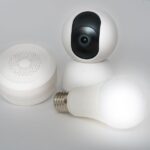 Aqara baisse ses verrous et caméras jusqu'à 37 % pour Black Friday 2025, mais Apple garde la clé A set of smart home devices including a camera, speaker, and lightbulb on a white background.