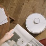 A sleek robot vacuum cleaner operating on a wooden floor, symbolizing modern home technology.