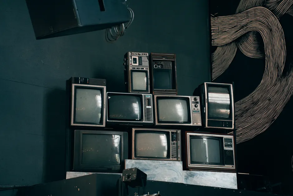 A stack of vintage CRT televisions in a dimly lit modern room with abstract art.