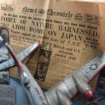 Pluribus : la bombe du final et les cookies de Tim Cook A vintage newspaper with an atomic bomb headline displayed alongside a model airplane and historic photos.