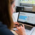 Apple change de pilotes : Alan Dye chez Meta, Giannandrea prend sa retraite A woman engineer focuses on software analysis using a laptop indoors.