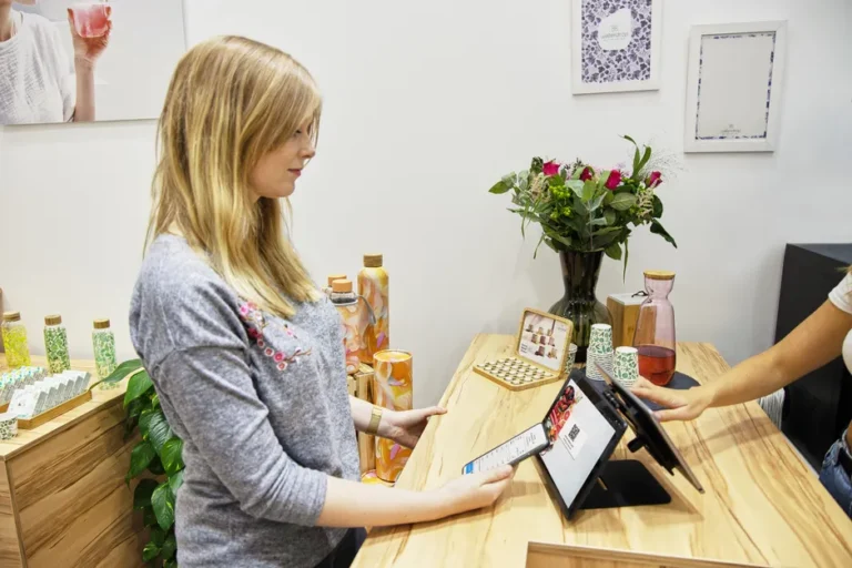 iPad 11 à 279 dollars le 16 décembre 2025 : le stock tranche A woman uses a tablet to make a payment in a stylish Berlin store, featuring modern decor and eco-friendly products.