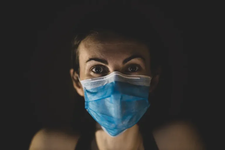 Apple Vision Pro M5, Apple Invites et vélo électrique: Apple déborde de l’iPhone en 2025 A woman wearing a blue surgical mask in a dark setting, highlighting healthcare themes.