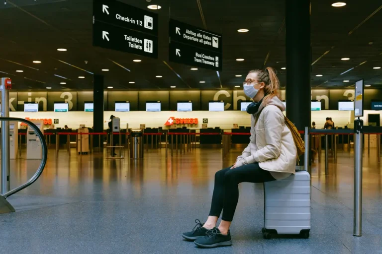 AirTag 2 : le suivi devrait gagner en précision en 2026, enfin A woman wearing a face mask sits on luggage in an airport terminal amid the pandemic.