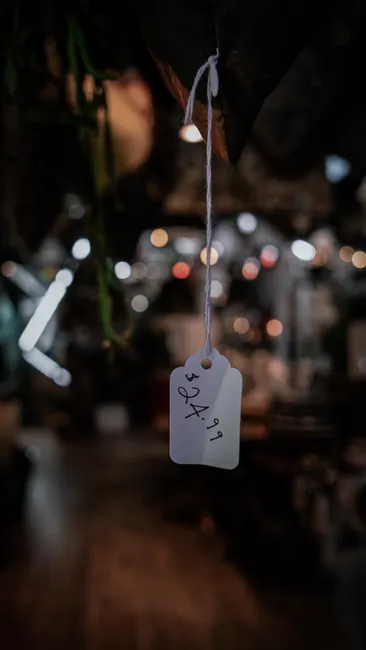 Artistic close-up of a hanging price tag in a dimly lit, blurred setting.
