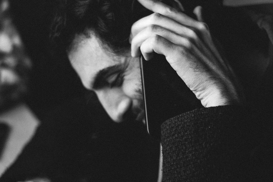 Black and white portrait of a man smiling while on a phone call, creating a relaxed mood.