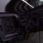 Apple Car Key arrive dans les Rivian R1 en décembre 2025, CarPlay reste au garage Close-up image of an electric vehicle charging port on a black car.