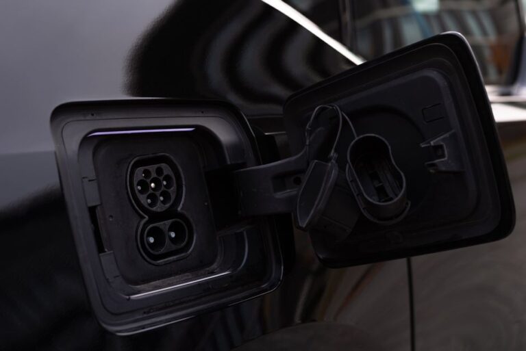 Apple Car Key arrive dans les Rivian R1 en décembre 2025, CarPlay reste au garage Close-up image of an electric vehicle charging port on a black car.