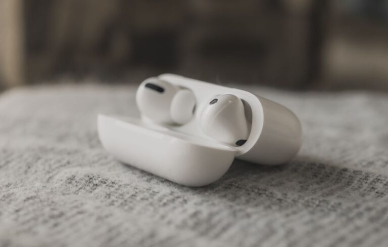 Close-up image of wireless earphones in a charging case on a textured surface.