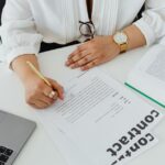 Netflix vise Warner pour 83 milliards : Ted Lasso reste sur Apple TV+, pour l'instant Close-up of a businesswoman signing a contract at her desk, with a laptop and book.