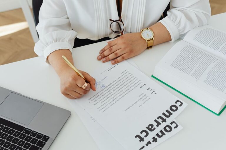 Netflix vise Warner pour 83 milliards : Ted Lasso reste sur Apple TV+, pour l’instant Close-up of a businesswoman signing a contract at her desk, with a laptop and book.
