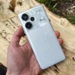 iPhone Air 2 en 2026? Le calendrier fait du yo-yo Close-up of a hand holding a modern white smartphone with dual lenses outdoors.