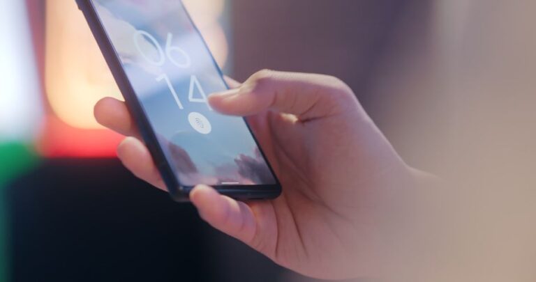 iPhone Fold en 2026 : Touch ID sur la tranche, le prix du millimètre Close-up of a hand holding a smartphone locked with a fingerprint sensor.