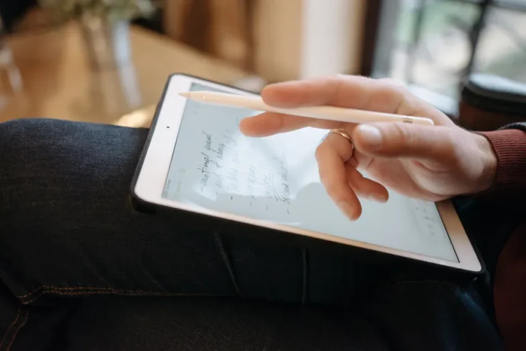 Boox Note Air5 C : 4 096 couleurs et Android 15, mais pas d’iPad de poche Close-up of a hand holding a stylus, writing on a tablet, featuring handwritten notes. Ideal for digital creativity concepts.