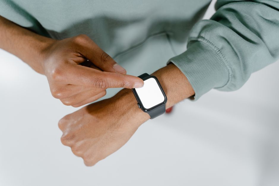 Close-up of a person in a green sweater using a smartwatch.