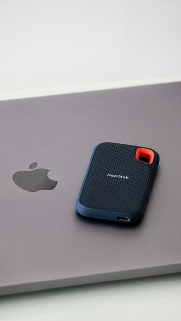 Close-up of a portable SanDisk external hard drive resting on a laptop surface, highlighting modern data storage solutions.