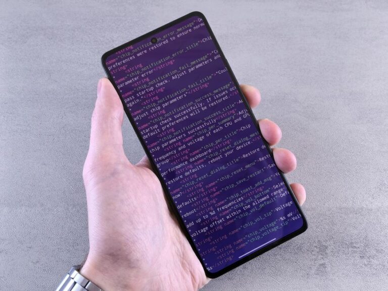 iOS 26.2 arrive le 12 décembre 2025 : AirDrop gagne un code Close-up of a smartphone displaying code text held in a person's hand.