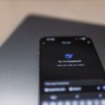 Close-up of a smartphone with AI assistant interface on screen over a laptop.