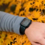 Apple Watch à 129 dollars au Black Friday 2025 : quel modèle choisir? Close-up of a smartwatch on a wrist surrounded by vibrant autumn leaves.