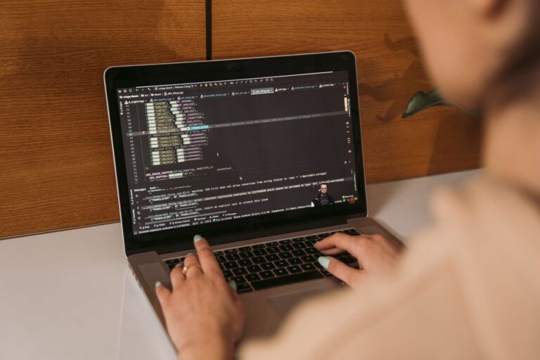 Docker sur Mac : le conteneur Linux passe par la VM Close-up of a woman coding using a laptop in an office environment, showcasing modern technology.