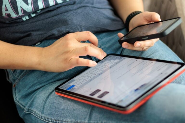iPadOS 26.2 arrive le 12 décembre 2025 : Slide Over respire enfin Close-up of adult using a tablet and smartphone indoors, showcasing digital connectivity and multitasking.