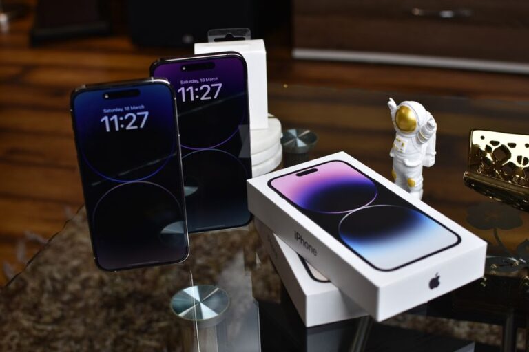 iPhone 14 Pro : 0,8 mm en 3D faciale, le volume fait sa diva Close-up of Apple iPhone 14 Pro Max with astronaut figurine on a reflective surface.