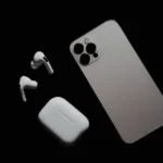 AirPods Pro comme appareil auditif : 35 participants, des gains mesurés Close-up of smartphone and wireless earbuds on a dark surface, showcasing modern tech gadgets.
