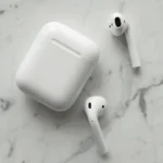 Close-up of wireless earphones and charging case on a marble surface, showcasing modern technology.