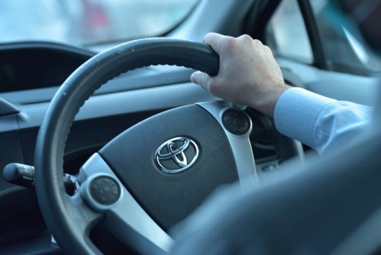 Apple Car Key Toyota : le signal du 15 décembre 2025, sans modèle confirmé Close-up view of a hand gripping a Toyota steering wheel in a car interior, Faisalabad, Pakistan.